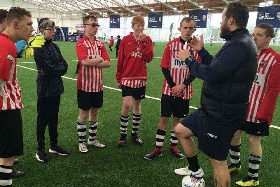 A group of footballers listening to a volunteer